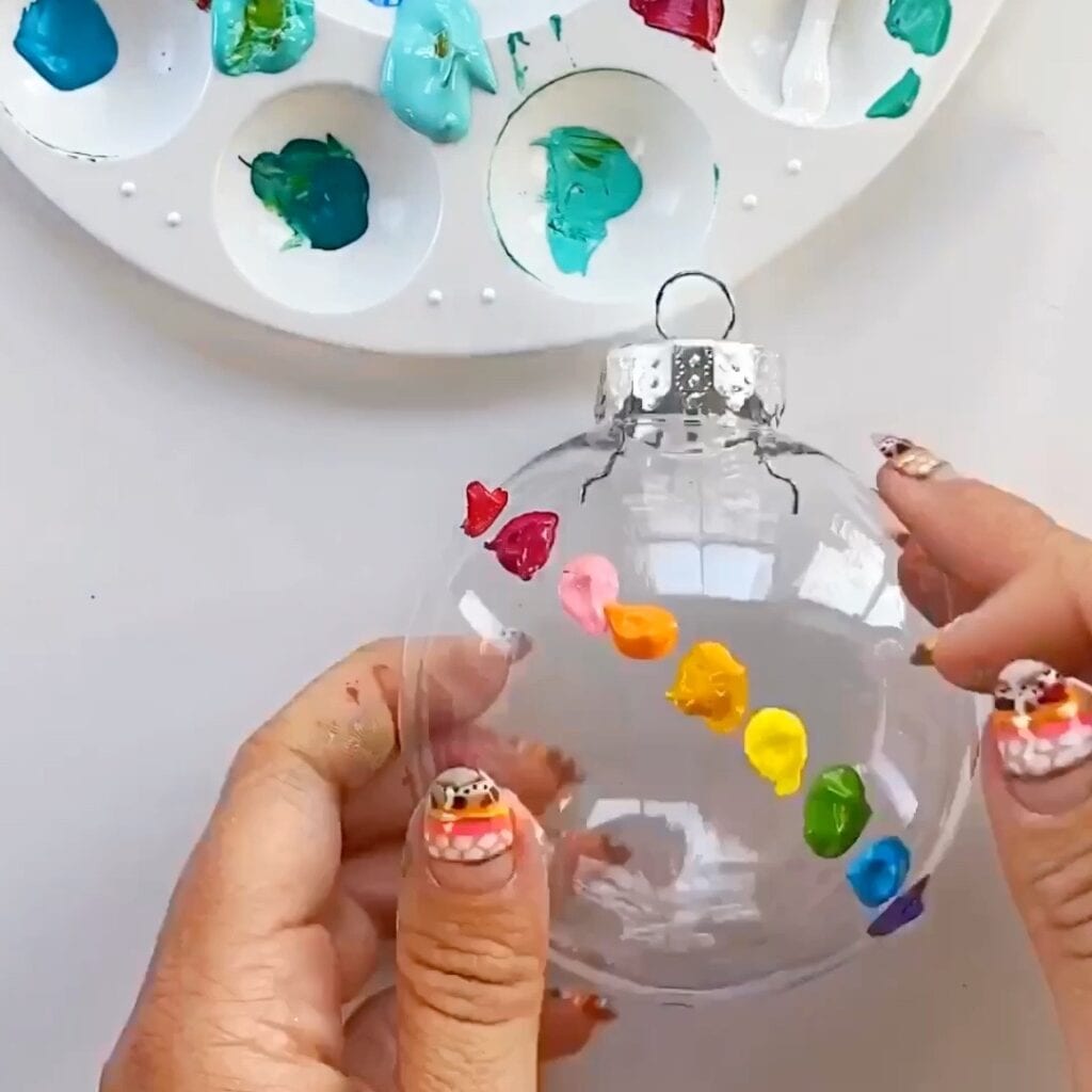 Clear ornament with rainbow of paint colors applied in blobs