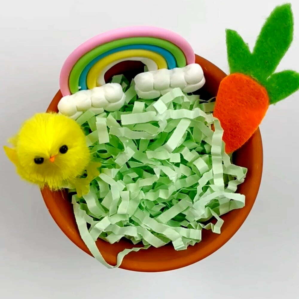 Flower pot with grass and a few accessories like a chick, rainbow, and carrot