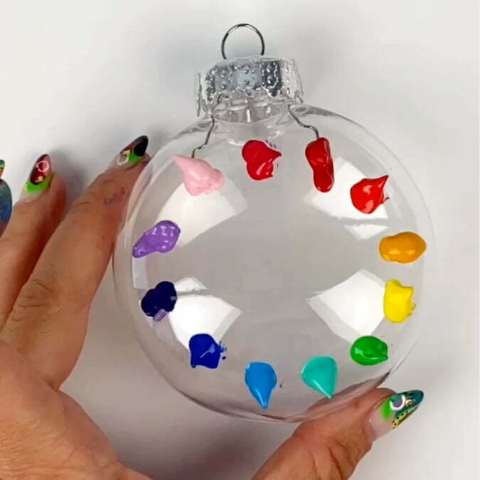 Rainbow of paint colors on an clear christmas tree ornament in blobs