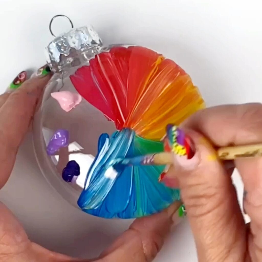 Spreading out the remaining paint colors across the DIY ornament to make a hand painted rainbow design