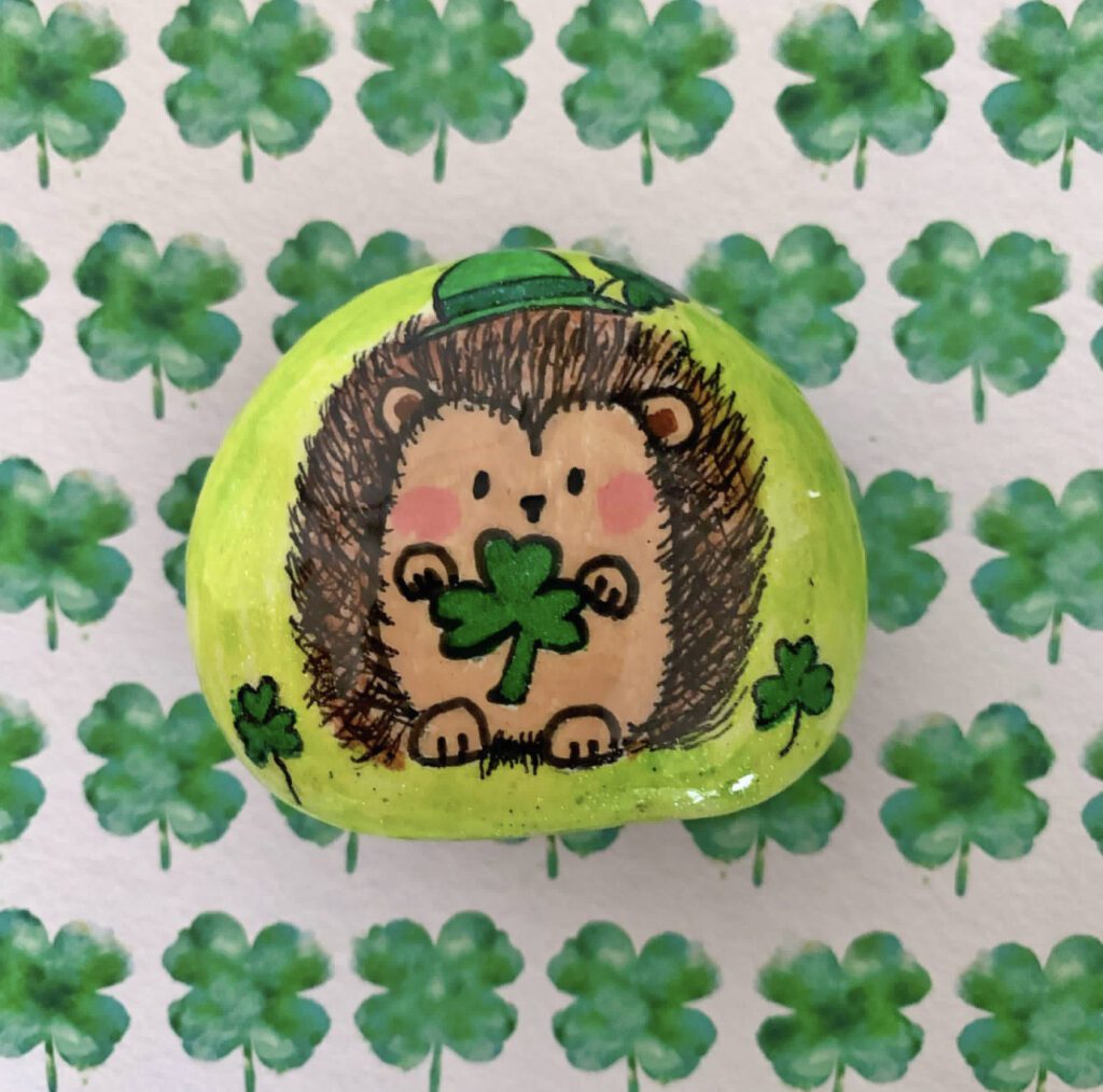 Hedgehog painted rock holding a shamrock