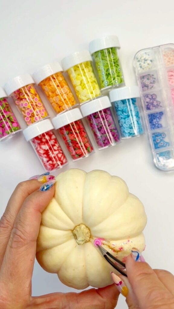 Applying nail art slices to a pumpkin